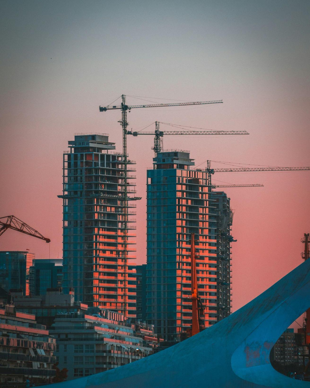 High-rise towers under construction with cranes, warm sunset light